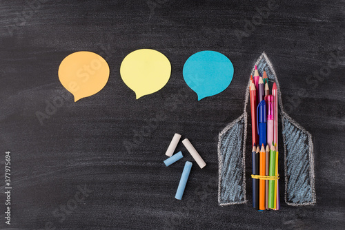 Photo of drawn rocket with colorful pencilc and pens chalk and three stickers isolated on classroom blackboard with copyspace