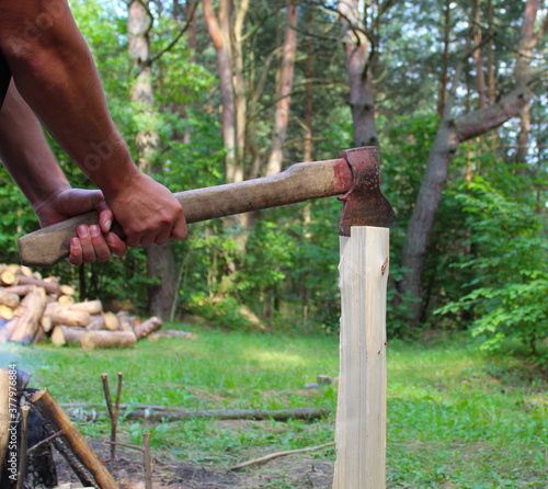chopping wood, with an ax in the hands of men, against the background of a fire and a forest