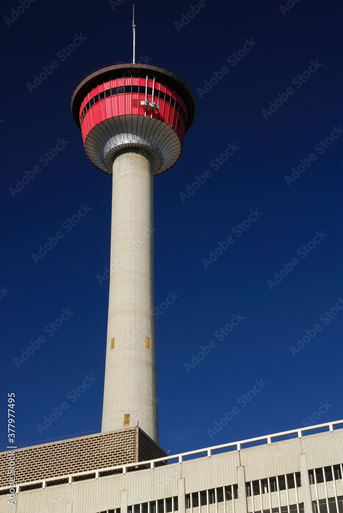 Calgary Tower against a deep blue sky with concrete building Calgary Tower against a deep blue sky with concrete building