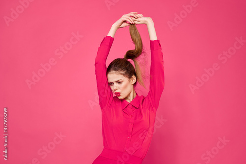 Portrait of a red-haired woman in bright clothes on a pink background cropped view of gesturing with her hands