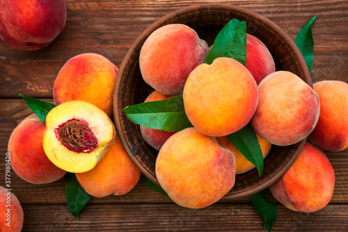 Ripe and tasty and juicy peaches lie on a plate on a wooden table. Large peaches on rustic wooden background, selective focus