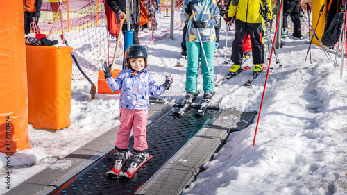 Young, happy skier girl going up on conveyor lift belt to green ski zone for ski lessons, Bialka Tatrzanska, Tatry, Poland