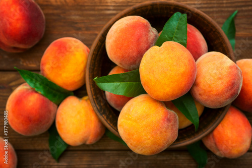 Ripe and tasty and juicy peaches lie on a plate on a wooden table. Large peaches on rustic wooden background, selective focus
