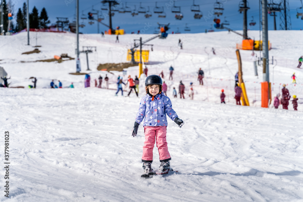Young happy skier girl learning how to ski on the green ski zone. Young skier having fun on ski slope, Bialka Tatrzanska, Tatry, Poland