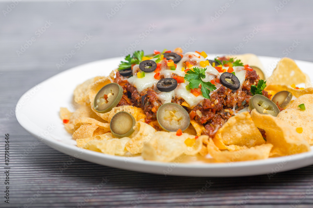 Mexican Famous Food Spicy Ground Beef Nachos. Heated crunchy tortilla chips with melted cheese and jalapeno served a snack food.