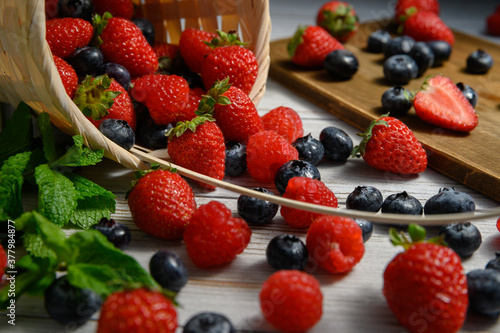 The berries spill out of the basket. strawberries and blueberries