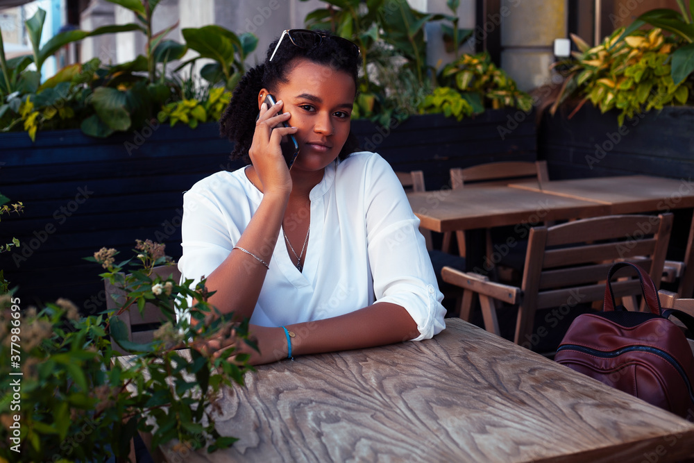 young pretty african girl posing cheerful in cafe outdoor, lifestyle people concept