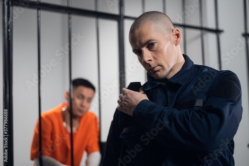 Fotografie A stern, bald prison warden makes the rounds of the cells and transmits informat