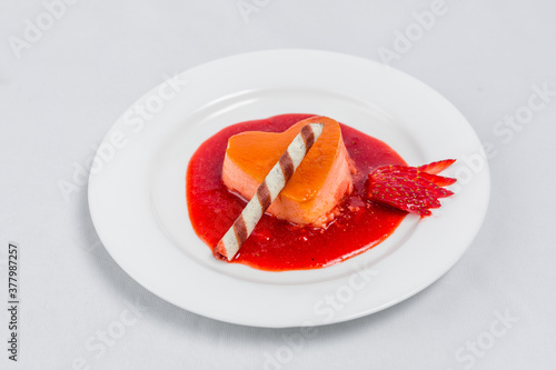 Heart-shaped pudding with strawberry sauce and wafer. Valentine's dessert recipe.