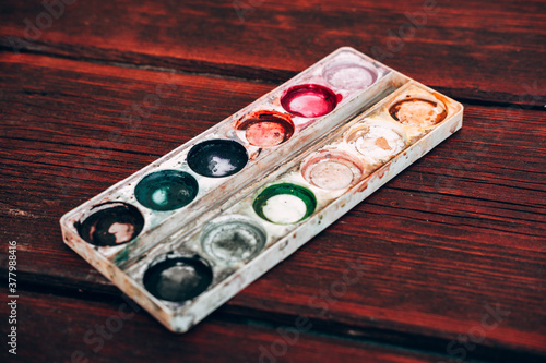 Art Palette with empty Colorful Paints Close up on a mahogany table. Empty and used multi-colored paint.