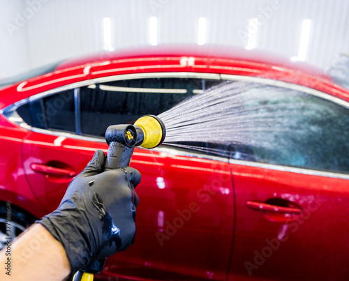 Service worker washing car on a car wash.