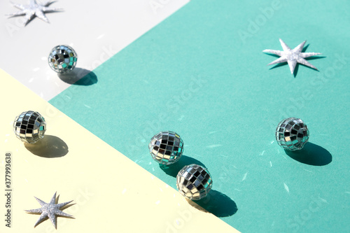 Mirror balls and silver Xmas stars on mint green and yellow layered paper. Geometric Christmas background, isometric view, direct hard light with shadows. photo