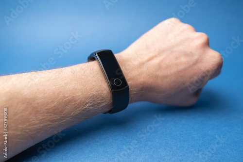 male hand with fitness bracelet on hand isolated on blue background