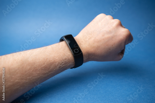 male hand with fitness bracelet on hand isolated on blue background