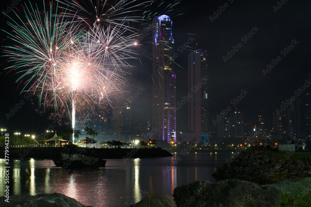 Die Skyline von Panama bei Nacht mit Feuerwerk am Idenpendence Day und Reflektionen der Lichter im Meer