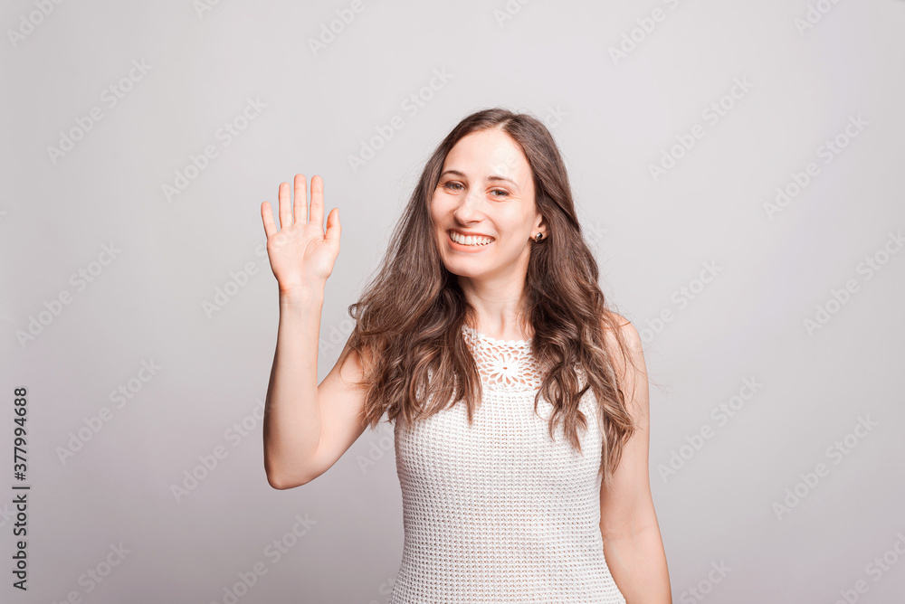 Portrait of joyful young woman making HELLO gesture Portrait of joyful young woman making HELLO gesture