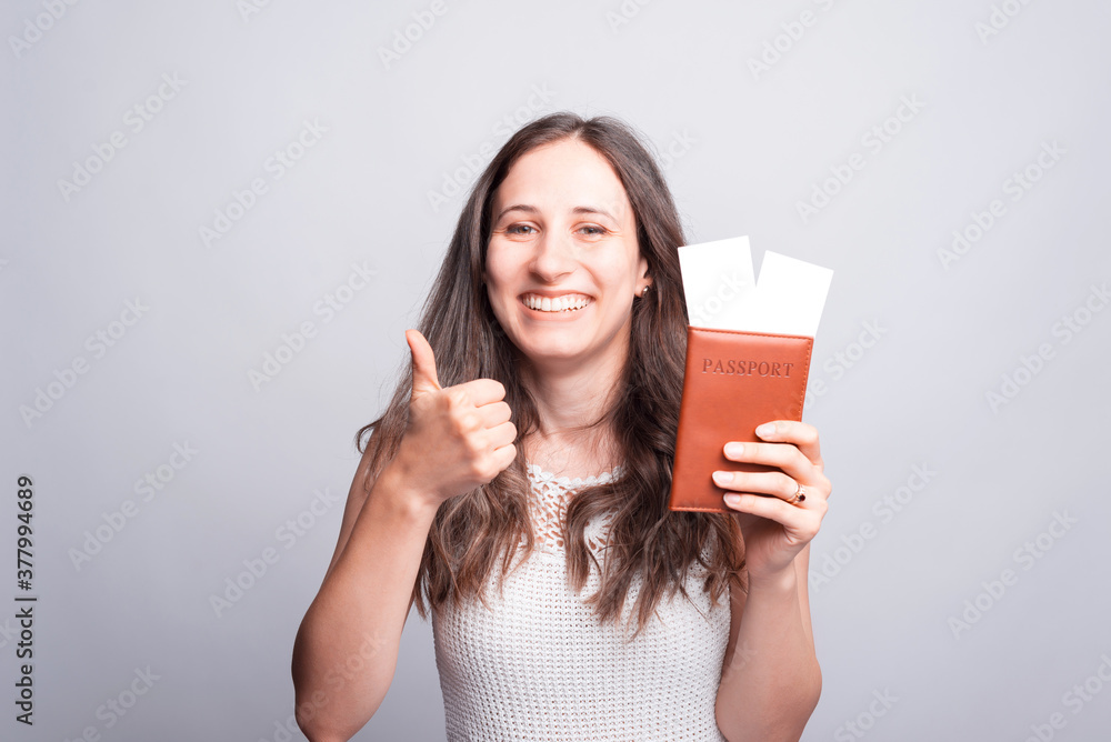 Portrait of happy woman showing thumb up and passport with flight tickets Portrait of happy woman showing thumb up and passport with flight tickets