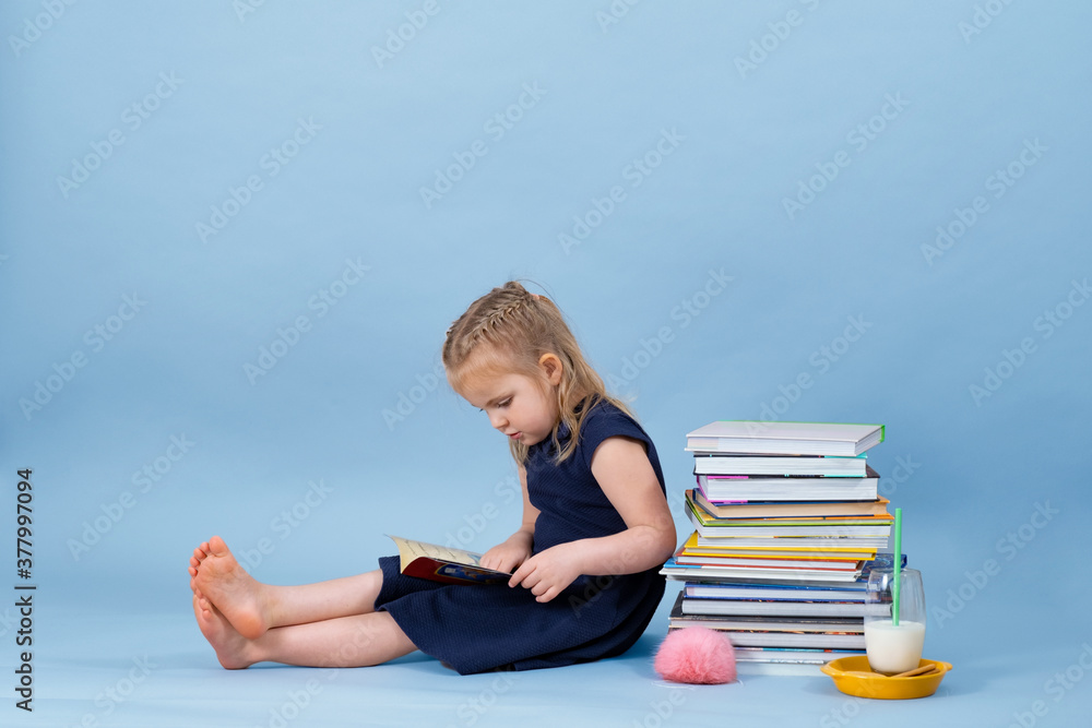 Fototapeta premium Girl is sitting on a books pile and enjoying her reading. 