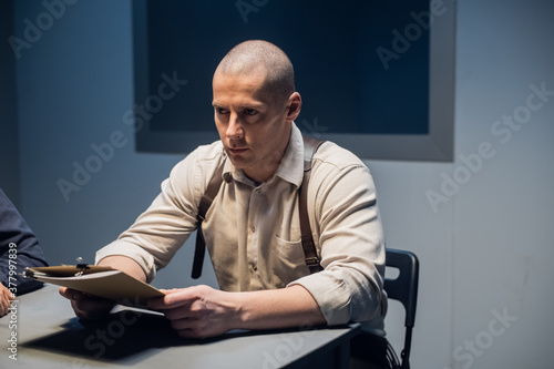 A close-up portrait of an experienced police officer sitting at a desk in uniform.