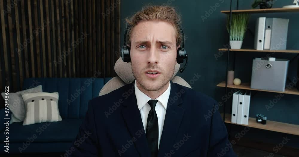 Confident Serious Business Vlogger, Mentor, Coach is holding Seminar, Webinar. Handsome Businessman is wearing Headphones with Microphone, getting Online Conference, Skype-Call. Online Education. Confident Serious Business Vlogger, Mentor, Coach is holding Seminar, Webinar. Handsome Businessman is wearing Headphones with Microphone, getting Online Conference, Skype-Call. Online Education.
