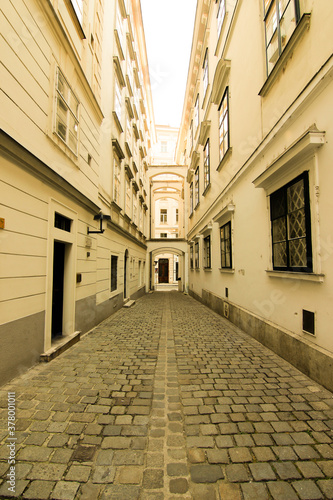 narrow stone street in the old town both sides with white houses and bridges connect houses © em1ncan