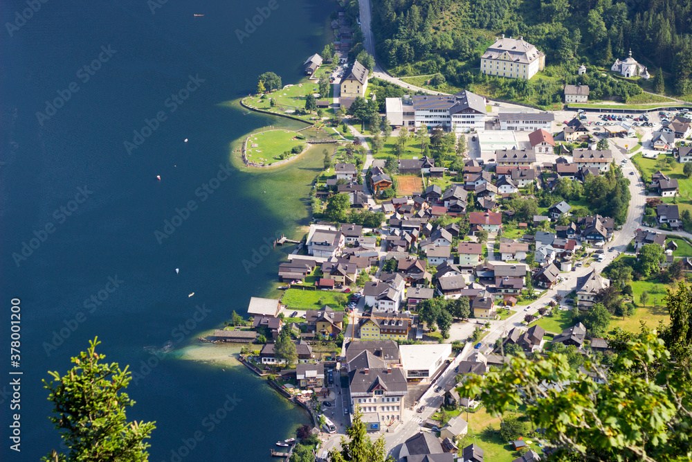 a town located by the lake in the mountains, popular touristical village hallstatt in Austria, boats on the lake, town 