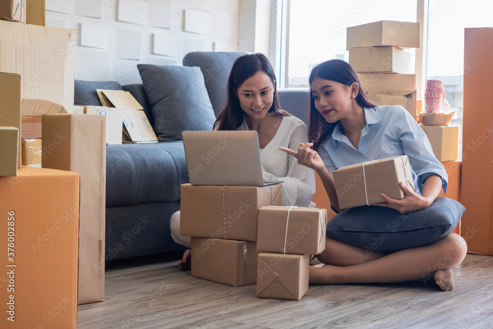 Fototapeta premium The young Asia Businesswoman makes parcel.They are makes it for order online.they are happy and smiles.Gift,Business,work woman,Freelance,happy,pleasure.Photo concept work and Shopping.
