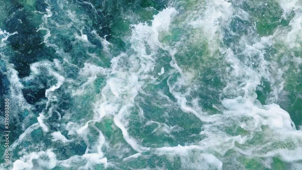Beautiful blue and green ocean waves crashing in slow motion with a lot of foam and spray. View from above, seamlessly looped. Beautiful blue and green ocean waves crashing in slow motion with a lot of foam and spray. View from above, seamlessly looped.