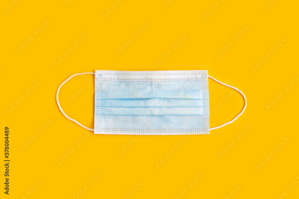 Surgical mask with rubber ear straps on yellow background. Surgical mask with rubber ear straps on yellow background.