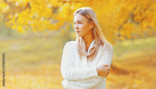 Portrait of beautiful young blonde woman in sunny autumn park