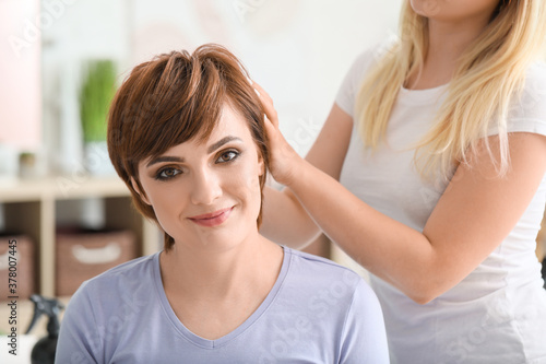 Professional hairdresser working with young woman in beauty salon