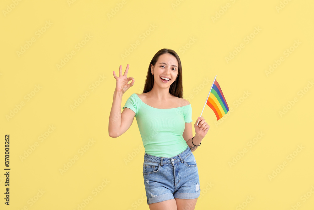 Young woman with LGBT flag showing OK on color background Young woman with LGBT flag showing OK on color background