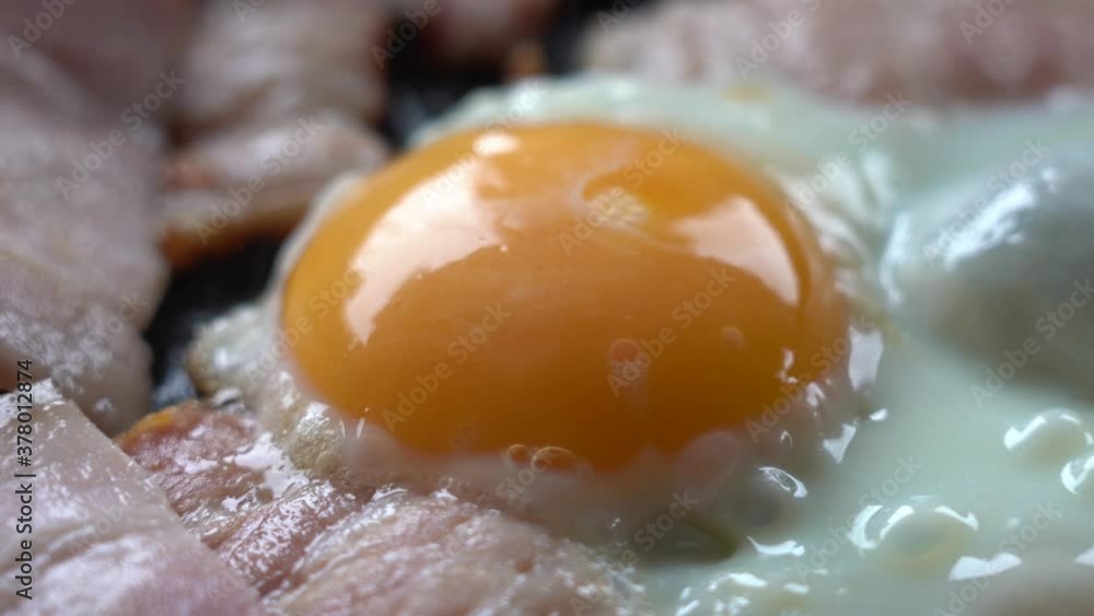 EGG and BACON are COOKED in a frying pan. Pieces of bacon and eggs in a hot frying pan, close-up. Natural Lighting from the window. EGG and BACON are COOKED in a frying pan. Pieces of bacon and eggs in a hot frying pan, close-up. Natural Lighting from the window.