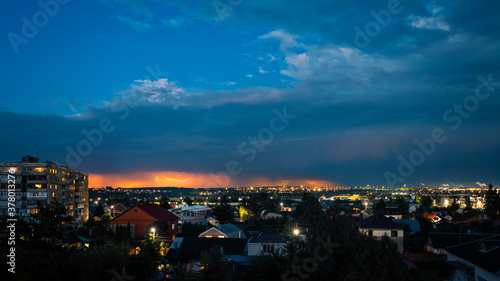 Bright yellow thunderbolts in the sky above the town in the evening, landscape.