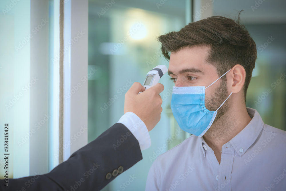 Body temperature check,Receptionist and guest wearing face mask at front desk while having conversation at hotel.Covid 19 and coronavirus infection protection and protective policy concept . - obrazy, fototapety, plakaty 