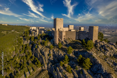 Dreamy cloudy sky above Jaen medieval Gothic castle and parador on an outcrop of a steep hill towering over the largest olive grove in the world photo