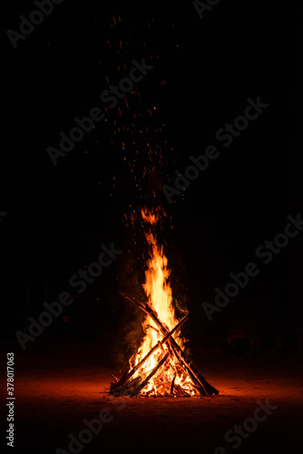 Camp fire in the night. Burning wood at night. Campfire at touristic camp at nature in dark. Flame amd fire sparks on black background. Hellish fire element. Fuel, power and energy