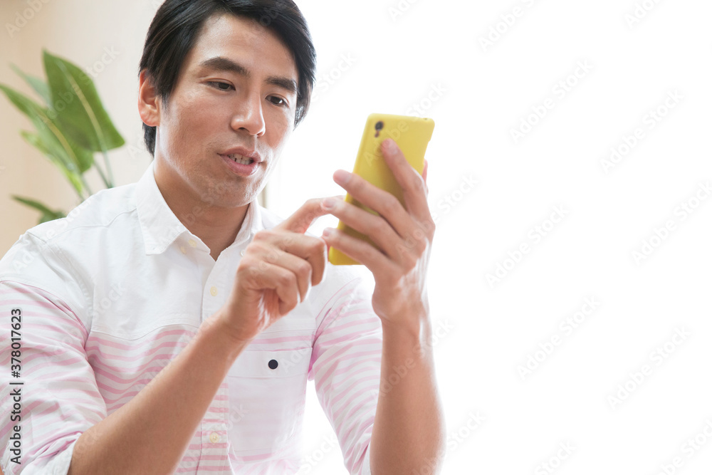 ソファに座ってスマホを見る男性 ソファに座ってスマホを見る男性