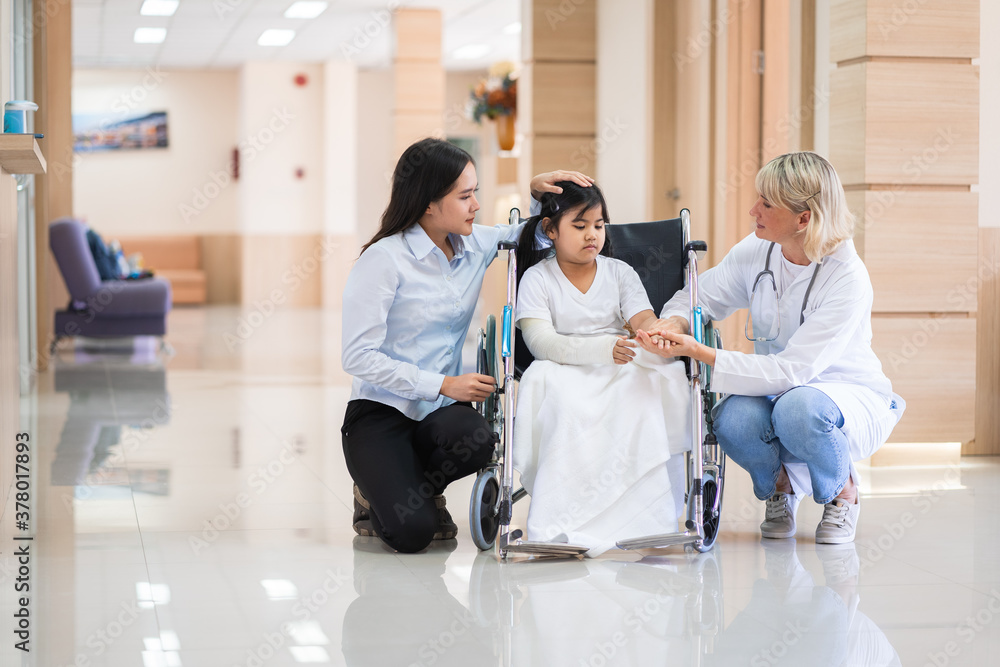 Fototapeta premium Female pediatrician doctor and child patient on wheelchair with her mother in the health medical center