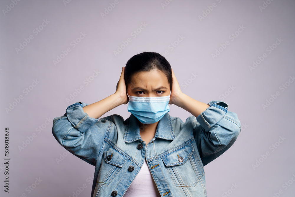 Asian woman wearing protective face mask and covering her ears by hands isolated over white background. Asian woman wearing protective face mask and covering her ears by hands isolated over white background.