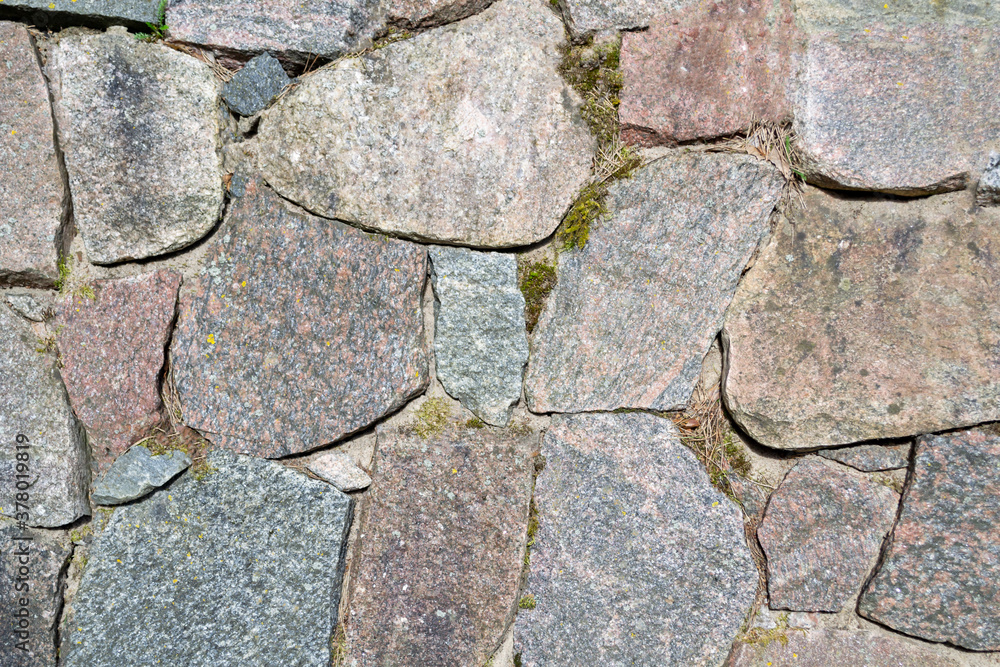 Obraz premium A wall made of large granite stones. Old stone wall. Natural material.