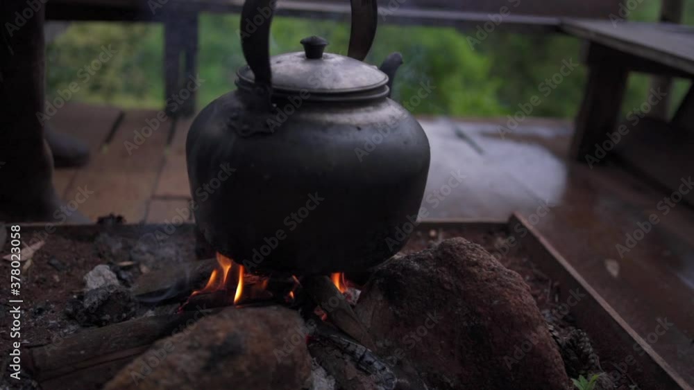 Slow motion close up shot of man hand holding old blackened kettle put on bonfire. Man preparing food on cottage terrace or outdoor kitchen.
Slow motion close up shot of man hand holding old blackened kettle put on bonfire. Man preparing food on cottage terrace or outdoor kitchen.