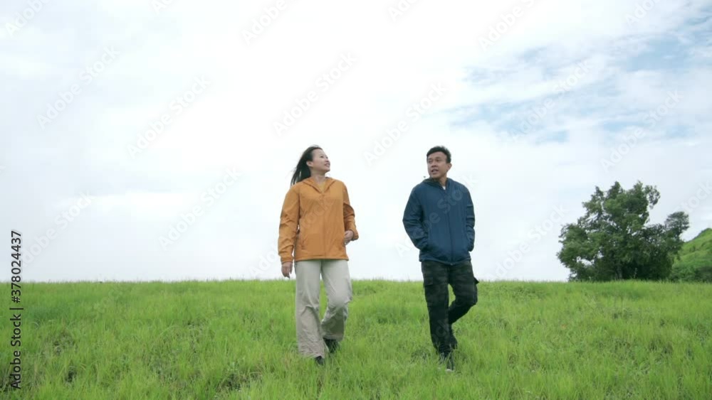 Young Asian woman with her boyfriend hiking together on mountain hill and standing at mountain peak with outstretched their hands against fresh air. Couple enjoy outdoor lifestyle and travel vacation. Young Asian woman with her boyfriend hiking together on mountain hill and standing at mountain peak with outstretched their hands against fresh air. Couple enjoy outdoor lifestyle and travel vacation.