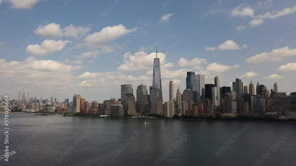A bird's eye view over Upper Bay with boats moving by in the waters below. The drone trucks right and pan left viewing Manhattan's financial district and westside. It is a sunny day and water is quiet A bird's eye view over Upper Bay with boats moving by in the waters below. The drone trucks right and pan left viewing Manhattan's financial district and westside. It is a sunny day and water is quiet