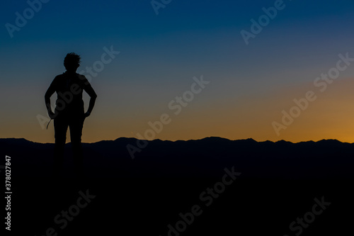 silhouette of a woman from the front with her arms on her hips in a sunset with the sky divided by yellow and blue © Paloma