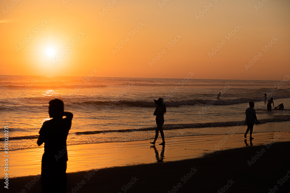 silhouette of people at the edge of the sea in a sunset