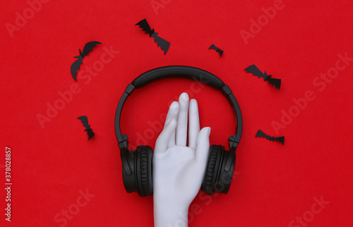Valokuva Mannequin hand and stereo headphones with bats on red background