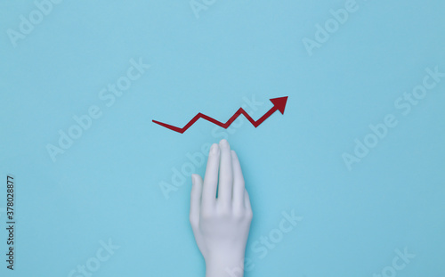 Mannequin's hand and red growth arrow tending upward on a blue background.