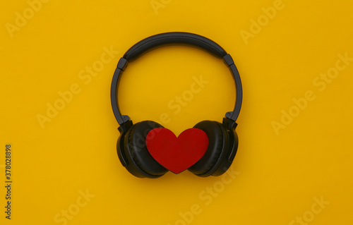 Stereo headphones with heart on yellow background. Music lover