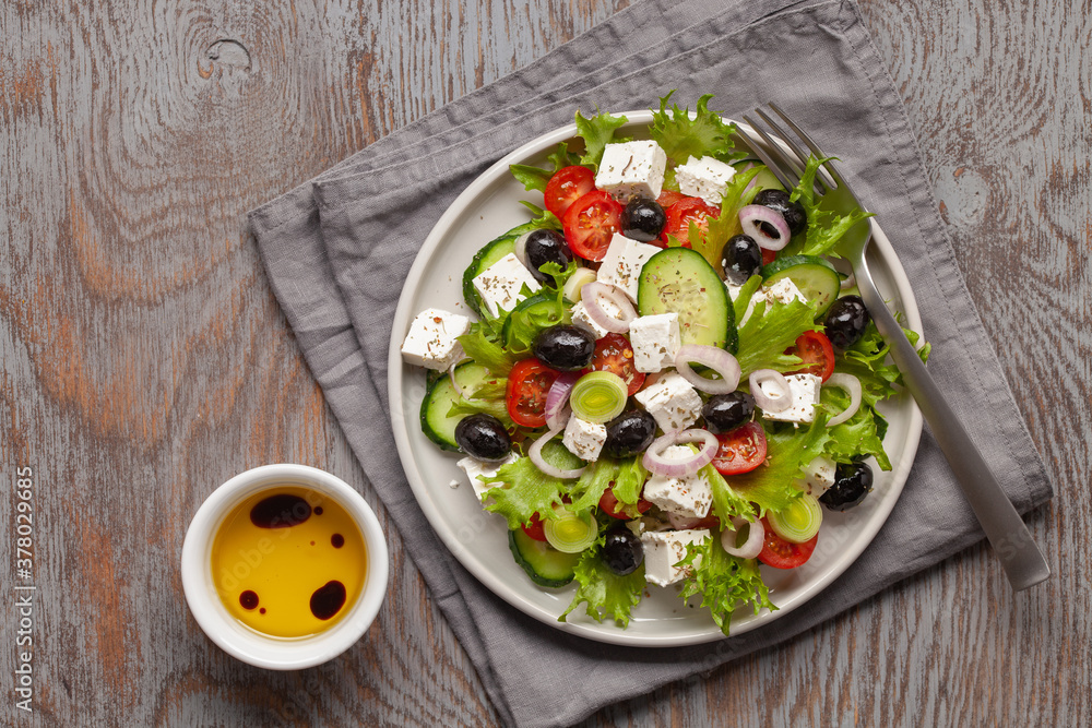 Greek salad of fresh cucumber, tomato, sweet pepper, lettuce, red onion, feta cheese and olives with olive oil. Healthy food, top view Greek salad of fresh cucumber, tomato, sweet pepper, lettuce, red onion, feta cheese and olives with olive oil. Healthy food, top view